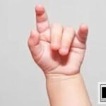 A close-up photograph of a young child’s hand forming the American Sign Language letter ‘I’ against a neutral grey background. The bottom-right corner features the DP HO Disable Persons Health Organization website logo.