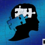 A silhouette of a human head in profile against a gradient blue puzzle piece background, suggesting concepts related to Autism and Visual Impairment. The top part of the brain area is depicted as interlocking white puzzle pieces, with loose blue puzzle pieces appearing to float away from the head, symbolizing the connection between cognitive processing and sensory perception. In the bottom right corner is a logo in a white box with black text that reads 'DP HO Disable Persons Health Organization.'
