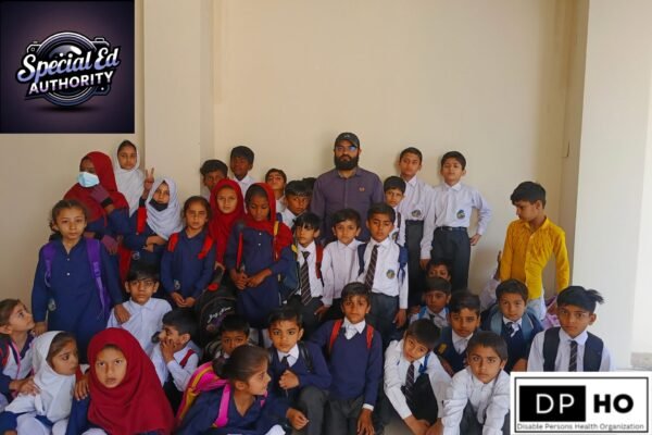A group photo of diverse students in school uniforms standing with their educator, Imtiyaz Ali, representing the dedicated staff and community at Disable Persons Health Organization (DP-HO).